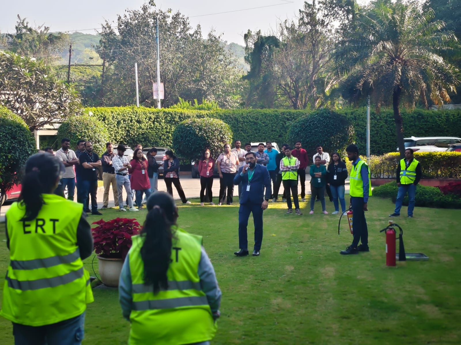 Outdoor safety briefing with Emergency Response Team members in hi-vis vests addressing staff on a lawn